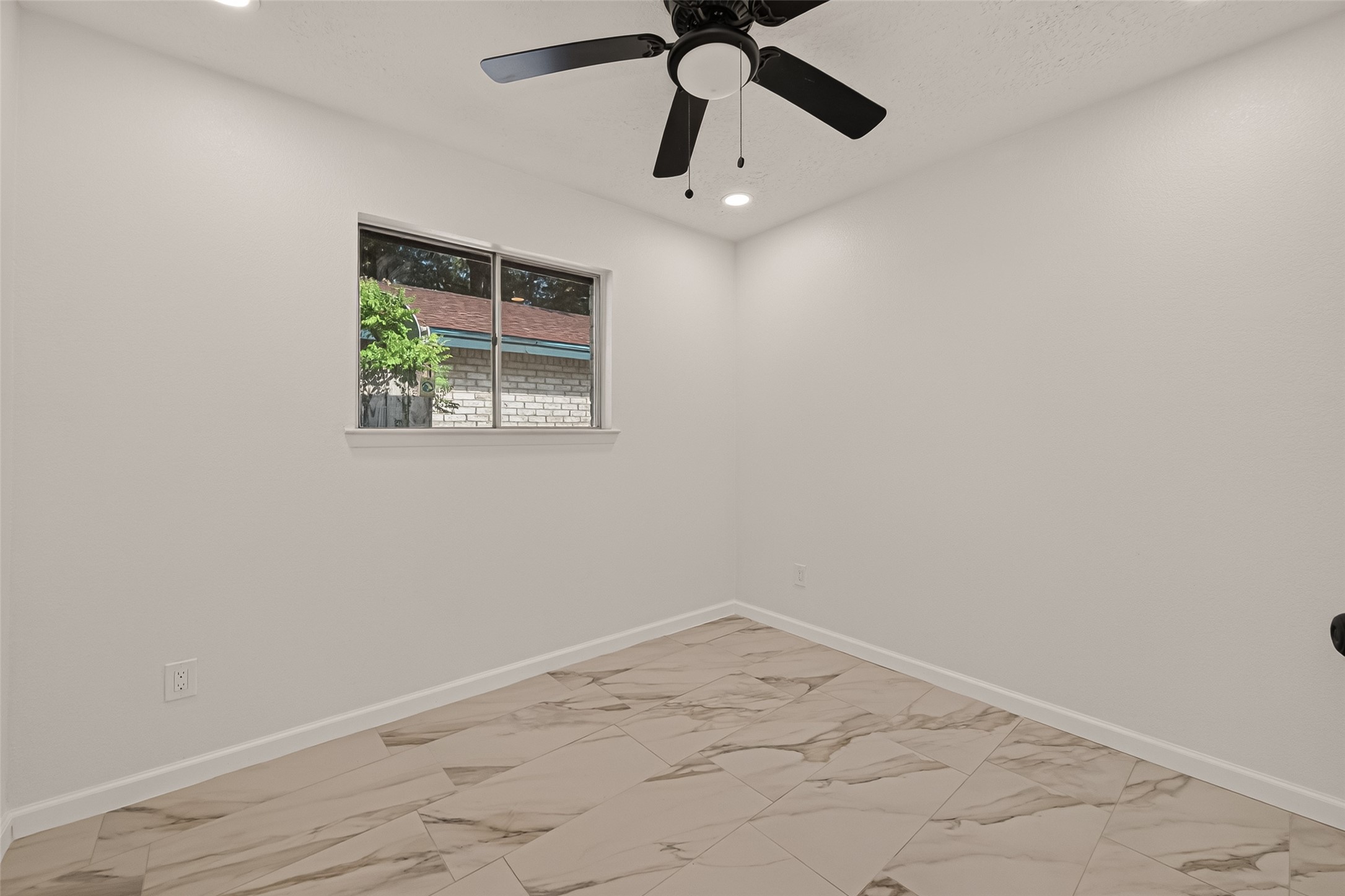 16619 Tibet Road Friendswood, TX 77546 - Photo 25 of 29 This room features a clean, modern design with light-colored walls and tile flooring. It includes a ceiling fan and a window providing natural light, creating a bright and airy atmosphere.
