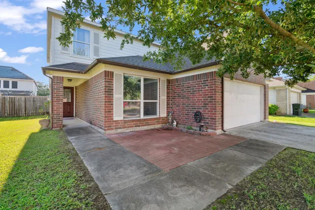 a view of a house with a yard and large tree