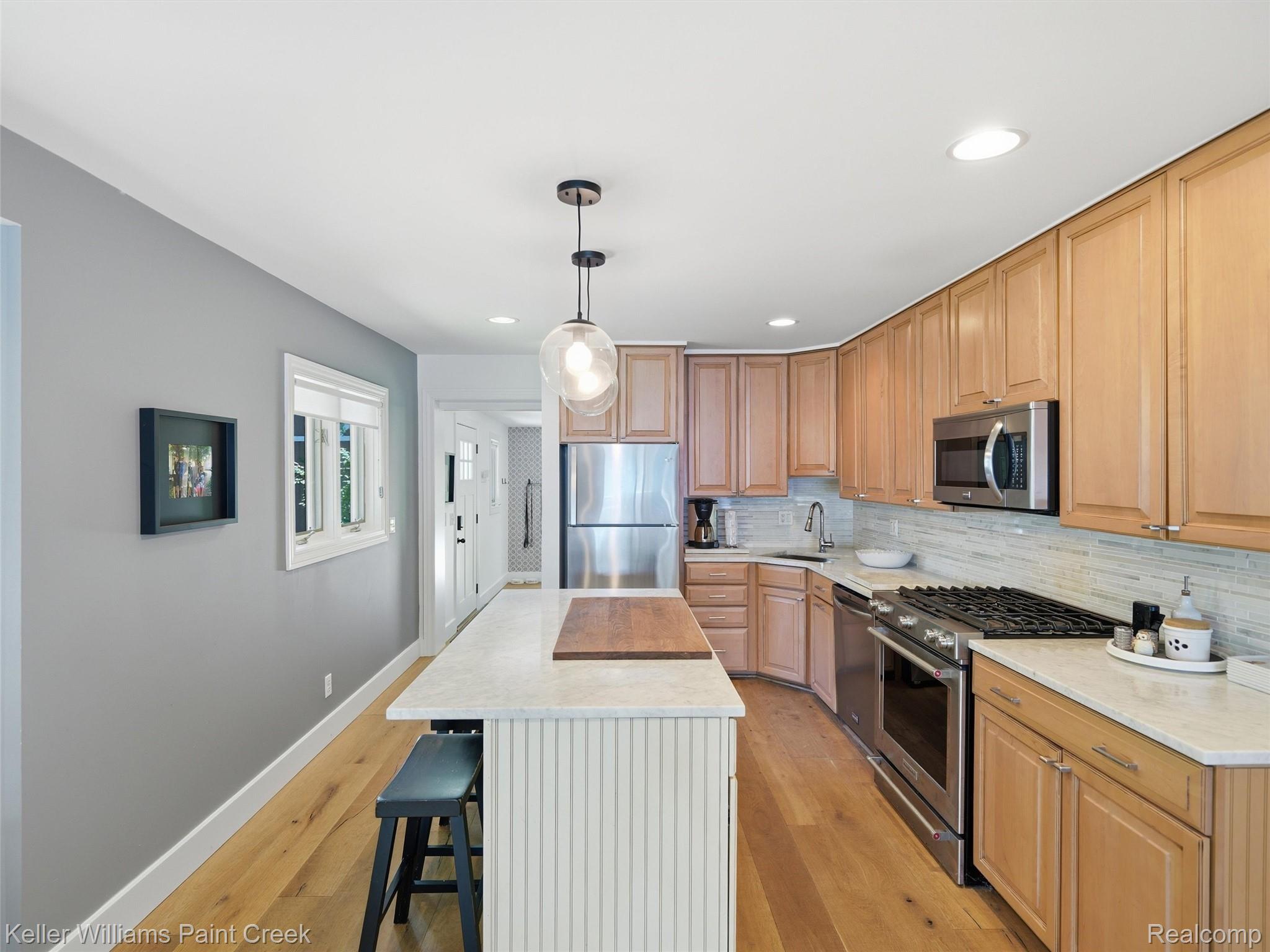 10435 Spring Street Fenton, MI 48430 - Photo 14 of 40 Bright kitchen featuring light wood cabinetry, stainless steel appliances, a center island with counter seating, and light wood-finish flooring