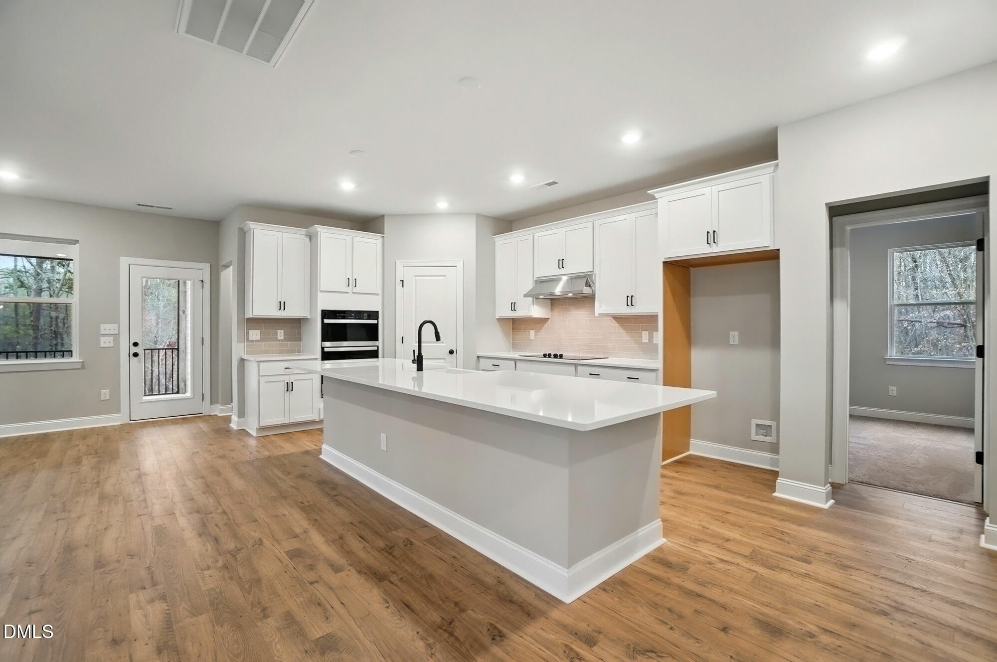 285 Gilliland Road Siler City, NC 27344 - Photo 12 of 45 a large kitchen with a center island wooden floor stainless steel appliances and windows