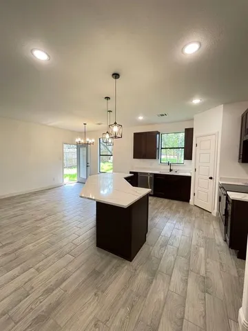 a kitchen with stainless steel appliances kitchen island granite countertop a stove and a wooden floors