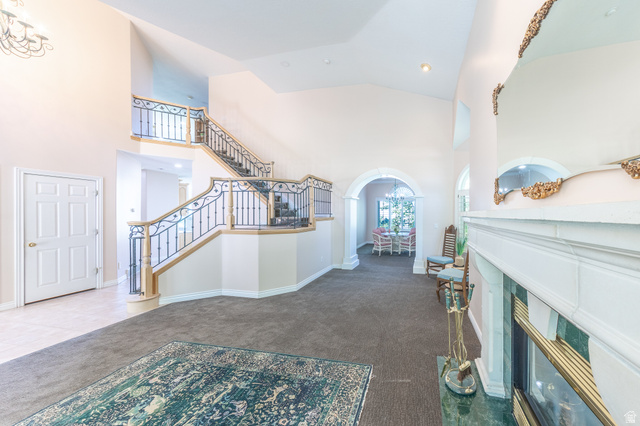 144 Bountiful Boulevard Bountiful, UT 84010 - Photo 14 of 28 Entryway featuring dark carpet, arched walkways, a high ceiling, a glass covered fireplace, and recessed lighting
