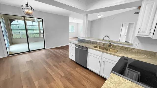 a kitchen with granite countertop a sink cabinets and wooden floor