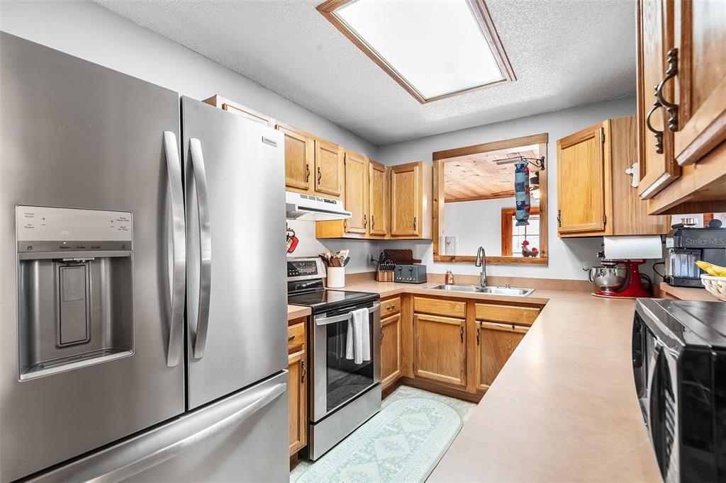 1233 St Anne Shrine Road Lake Wales, FL 33898 - Photo 9 of 47 a kitchen with stainless steel appliances granite countertop a refrigerator a sink dishwasher a stove and white countertops with wooden floor