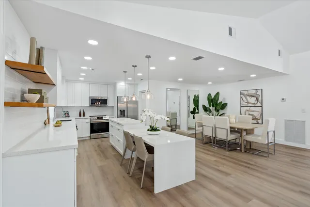 a kitchen with stainless steel appliances kitchen island wooden floors stove and white cabinets