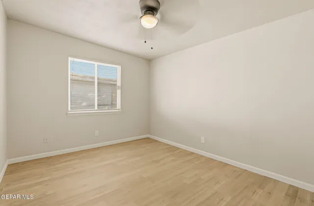 an empty room with wooden floor and chandelier fan