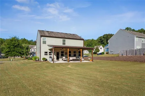 a view of a house with a big yard and large trees