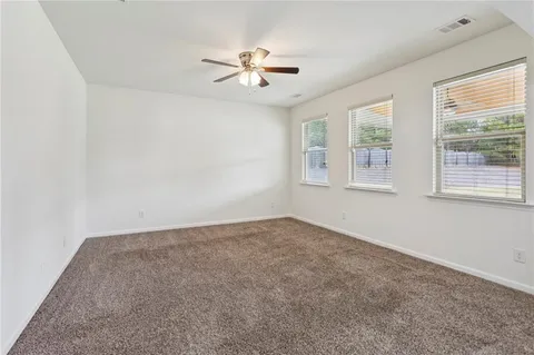 an empty room with windows and chandelier fan