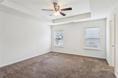 an empty room with a chandelier fan and windows