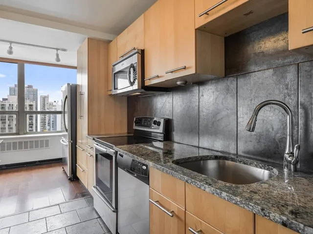a kitchen with stainless steel appliances granite countertop a sink a stove and a refrigerator