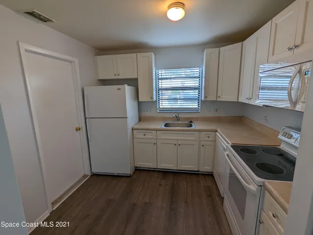a kitchen with a sink a refrigerator and cabinets