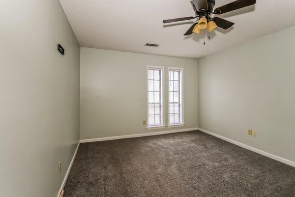 an empty room with windows and fan