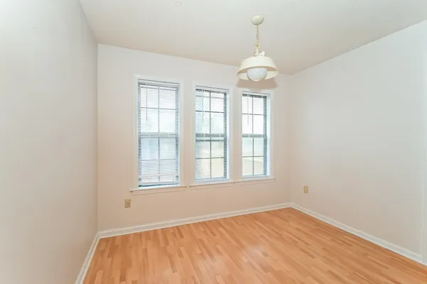an empty room with wooden floor windows and fan