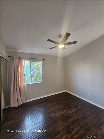 an empty room with wooden floor fan and windows
