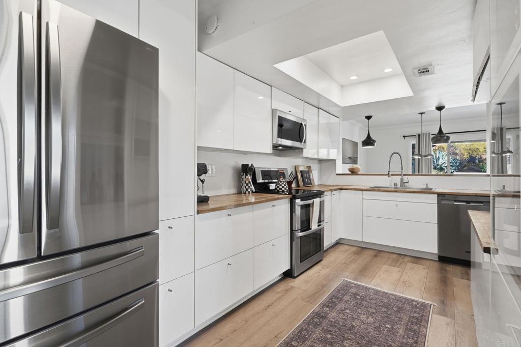 2972 Lancaster Road Carlsbad, CA 92010 - Photo 14 of 36 a kitchen with white cabinets and stainless steel appliances