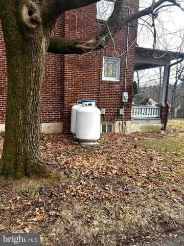 a view of a brick wall with windows and tree in front of it
