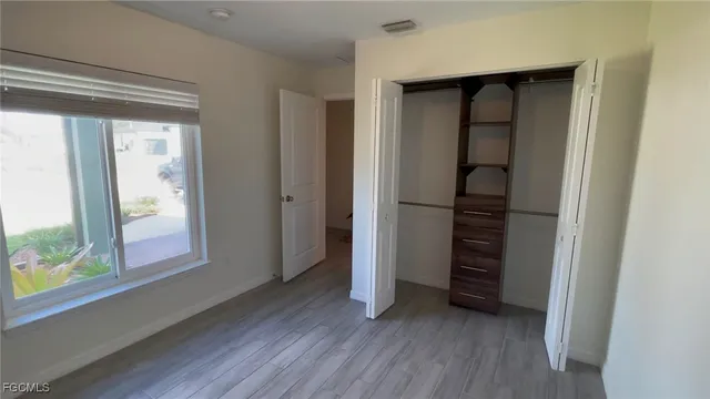 an empty room with wooden floor closet and windows