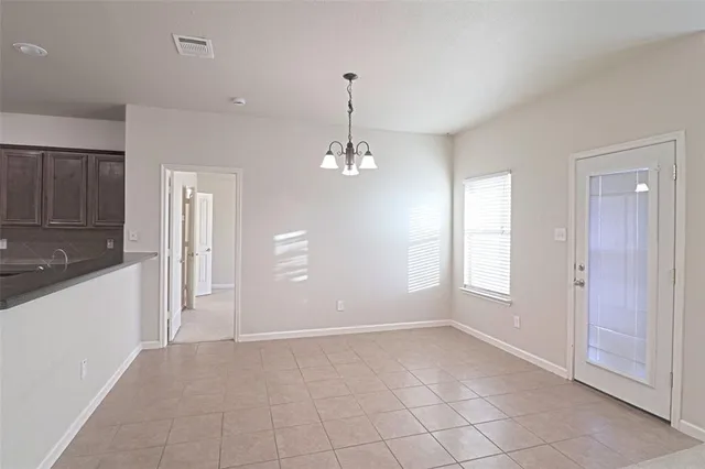 an empty room with chandelier and windows