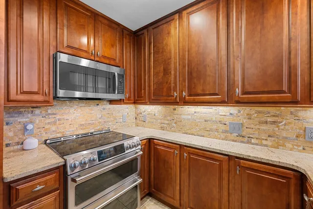 a kitchen with granite countertop wood cabinets stainless steel appliances and sink