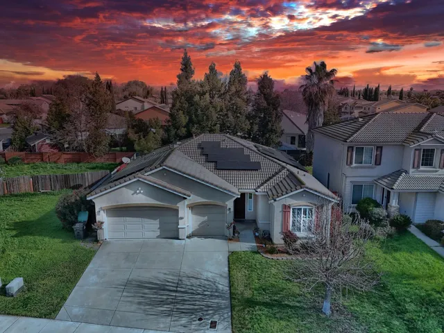 a front view of a house with a yard and mountain view in back
