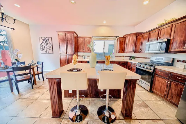 a large white kitchen with a stove a sink and a dining table
