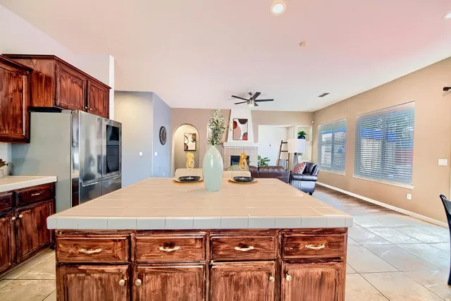 a living room with stainless steel appliances kitchen island granite countertop a dining table chairs and a refrigerator