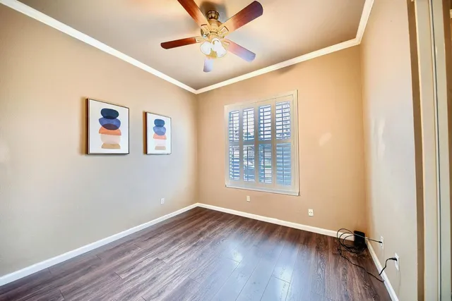 an empty room with wooden floor chandelier fan and windows