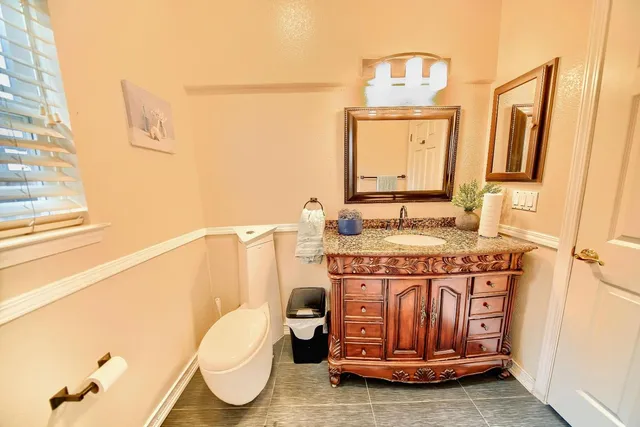 a bathroom with a granite countertop sink a toilet and a mirror