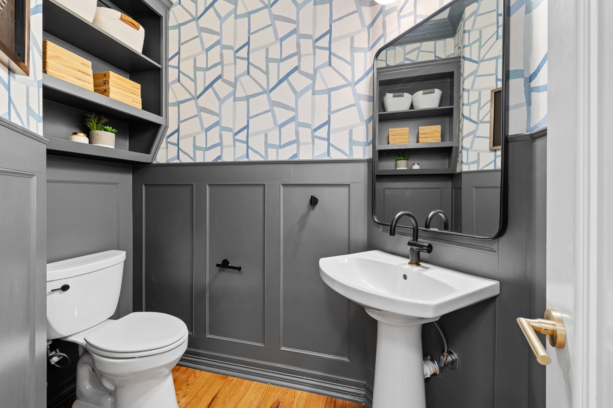 520 Oxford Street, Unit F Houston, TX 77007 - Photo 14 of 38 The fully remodeled first-floor powder room is a standout space featuring bold board-and-batten paneling in a deep charcoal finish, graphic wallpaper, a pedestal sink with matte black fixtures, and custom built-in shelving. Every detail of this 2022 renovation was thoughtfully designed to make a lasting impression.