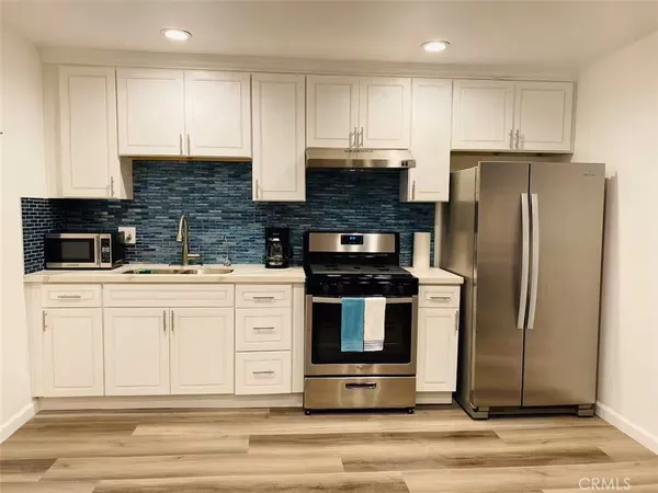 a kitchen with stainless steel appliances granite countertop a stove top oven a refrigerator and a dining table