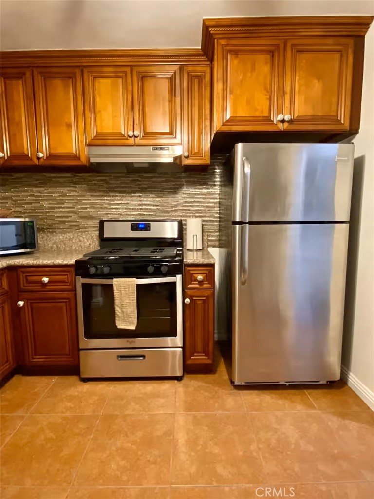 1364 East 61st Street Los Angeles, CA 90001 - Photo 6 of 32 a kitchen with granite countertop a refrigerator and a stove top oven