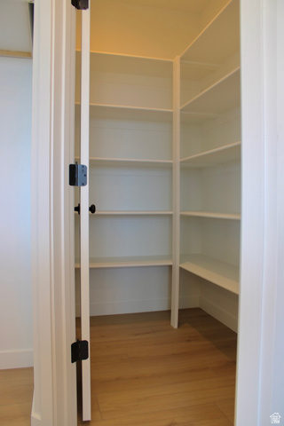 2613 Scarlet Road, Unit 258 Eagle Mountain, UT 84005 - Photo 9 of 32 Walk-in pantry featuring white shelving, wood-finish flooring, and a white paneled door with black hardware