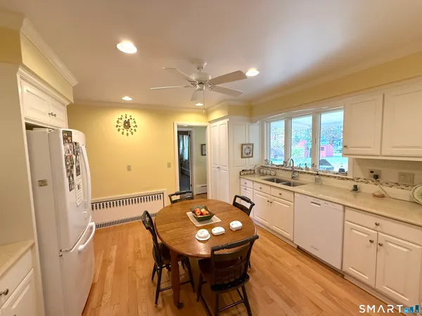 a kitchen with stainless steel appliances granite countertop a refrigerator a sink dishwasher a stove and white countertops with wooden floor