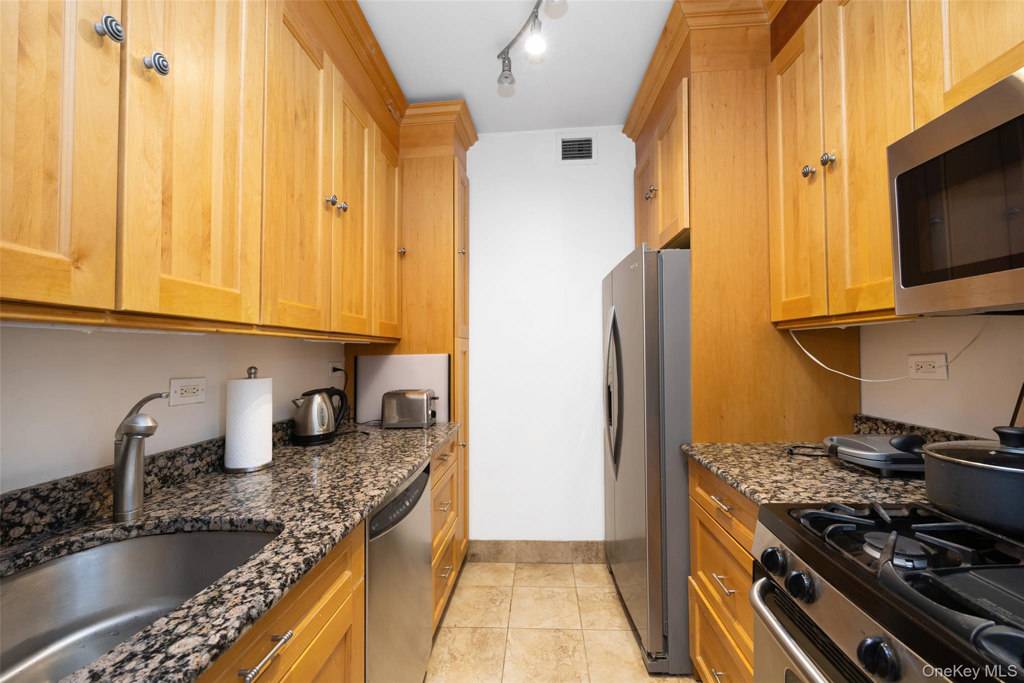 380 Rector Place, Unit 7A Manhattan, NY 10280 - Photo 11 of 19 Kitchen with a sink, dark stone counters, stainless steel appliances, baseboards, and visible vents