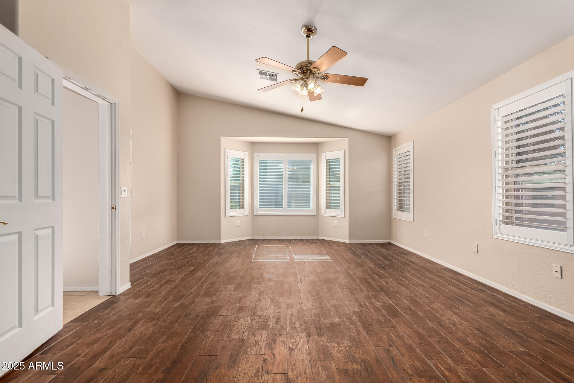 2513 West Carter Road Phoenix, AZ 85041 - Photo 4 of 27 a view of an empty room with wooden floor and a window