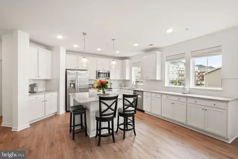a kitchen with stainless steel appliances kitchen island granite countertop a dining table chairs and sink