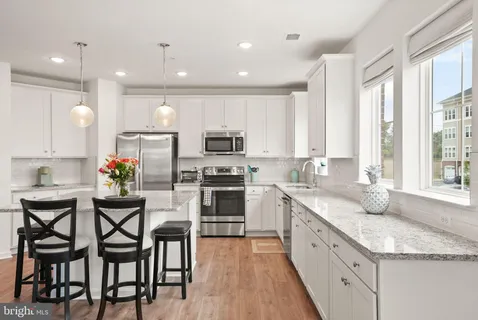 a kitchen with stainless steel appliances granite countertop a table chairs refrigerator sink and cabinets