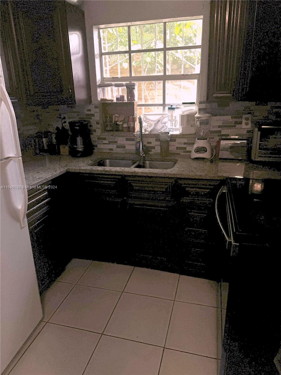 655 Northeast 80th Street Miami, FL 33138 - Photo 15 of 19 a kitchen with a sink a stove a microwave and cabinets