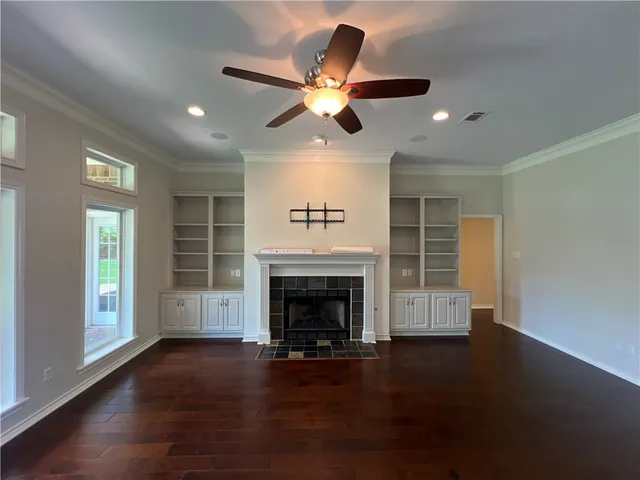 a view of a livingroom with a fireplace a ceiling fan and wooden floor