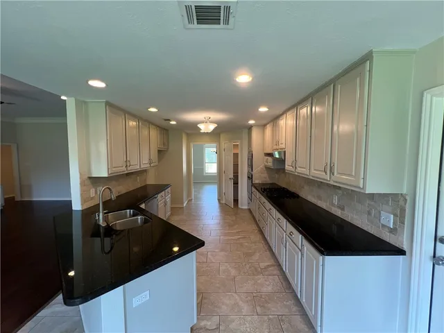 a kitchen with granite countertop sink and cabinets