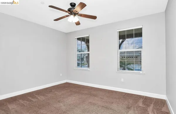 an empty room with chandelier fan and windows