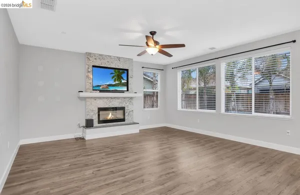 a view of an empty room with wooden floor fireplace and a window