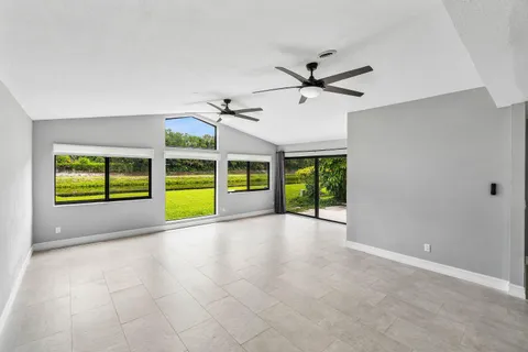 a view of an empty room with a window and kitchen view