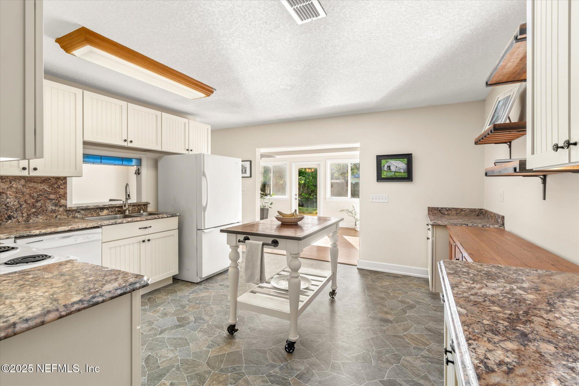 904 San Jose Road St. Augustine, FL 32086 - Photo 8 of 31 a kitchen with a dining table chairs and a refrigerator