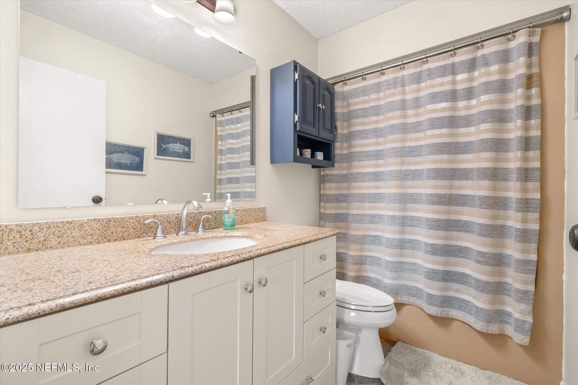 904 San Jose Road St. Augustine, FL 32086 - Photo 10 of 31 a bathroom with a granite countertop sink a toilet and a mirror