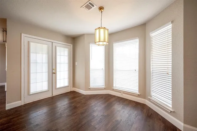 a view of an empty room with wooden floor and windows
