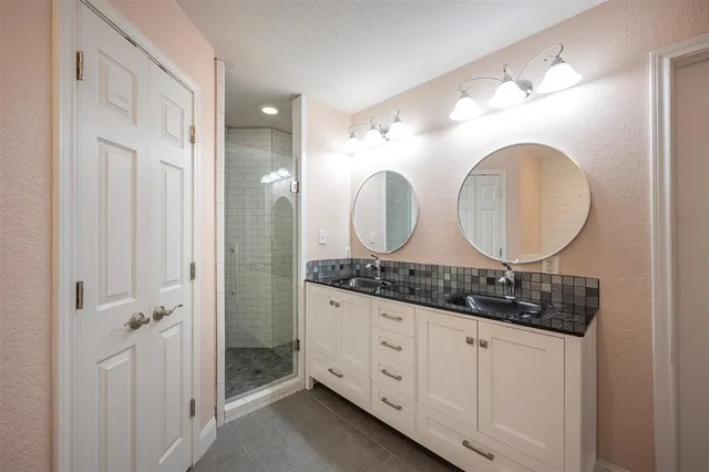 a bathroom with a granite countertop double vanity sink and a mirror