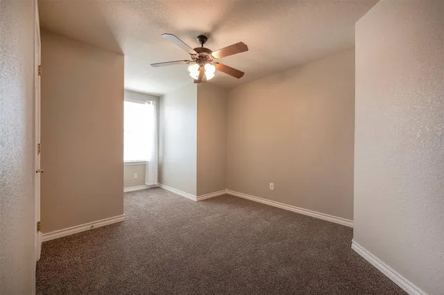 a view of an empty room with a chandelier fan