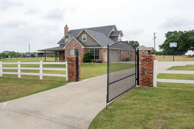 a view of a house with a yard and a large tree