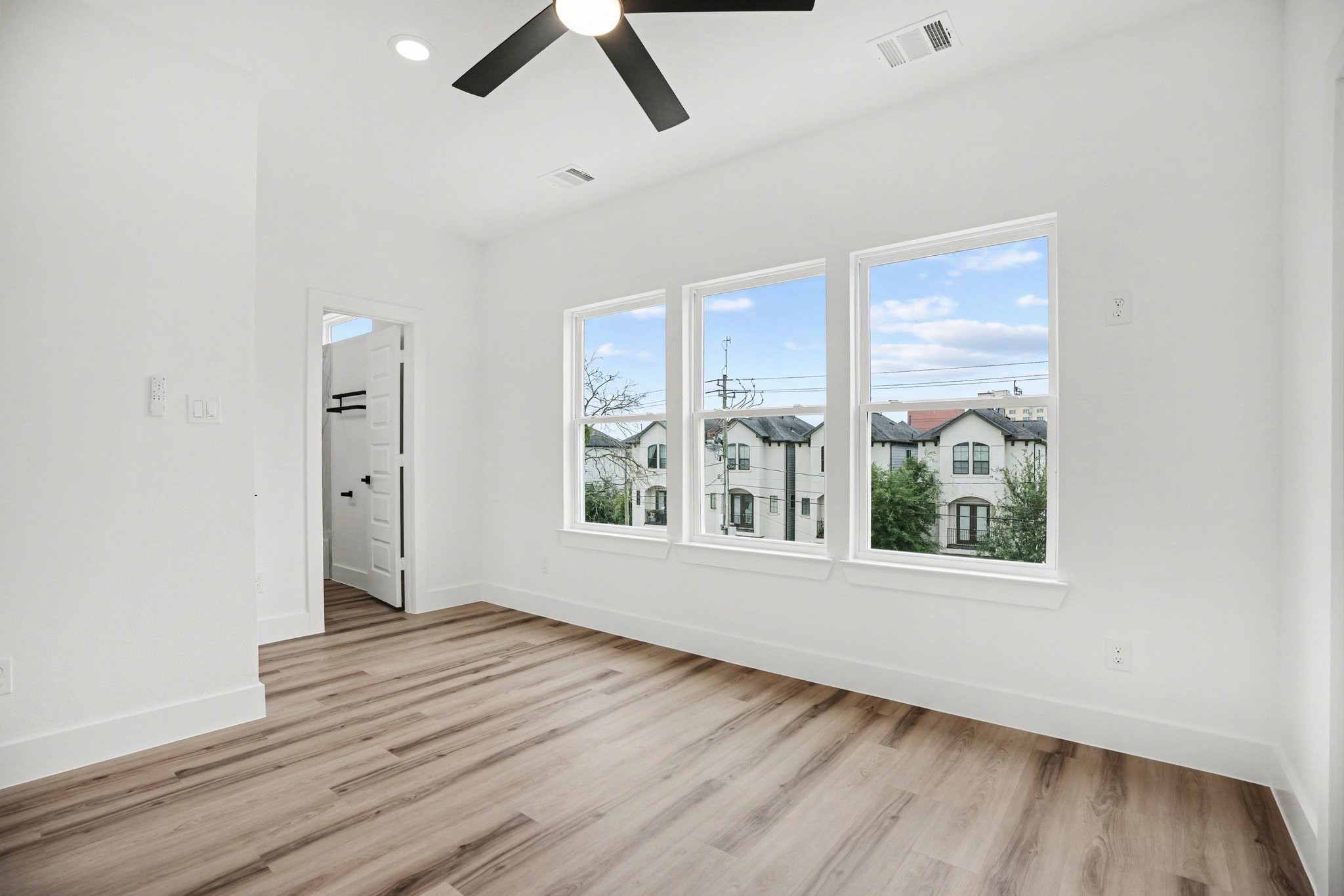 115 Milby Street Houston, TX 77003 - Photo 22 of 28 Bright room with large windows, wood-look flooring, and a ceiling fan. Ideal for a bedroom or office.